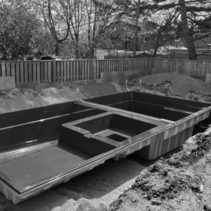 Backyard fiberglass pool shell in excavation